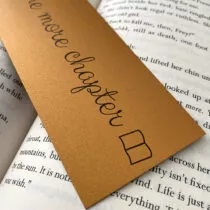 detailfoto van gouden boekenlegger met een opengeslagen boek en de tekst just one more chapter