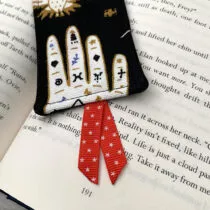 detailfoto van zwarte boekenlegger met daarop een hand en twee rode lintjes met sterretjes aan de onderkant