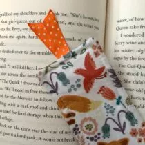 detailfoto van witte boekenlegger met vosjes en verschillende kleuren bloemen met aan de bovenkant 2 oranje lintjes met witte stippen