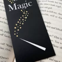 detailfoto van zwarte boekenlegger met daarop een witte toverstaf met sterren in goud folie en de tekst magic