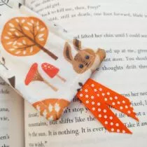 detailfoto van creme kleurige boekenlegger met een boom een konijn en paddenstoelen met een oranje lintje met witte stippen aan de onderkant