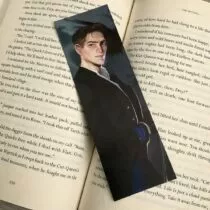 detailfoto van boekenlegger van Kaz. Met grijze achtergrond, kaz draagt een zwarte lange jas