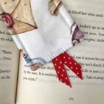 detailfoto van witte boekenlegger met magische objecten, een brief en een stukje ketel. Met rood lintje met sterretjes aan de onderkant