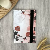 bookjacket met wit rode achtergrond en rozen met zwarte takken, bladeren en doorns. Met een zwart elastiek