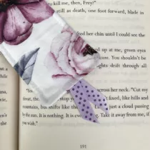 detailfoto van witte boekenlegger met licht roze bloem en paars lintje met donkerpaarse stippen