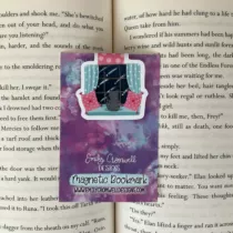 magnetische boekenlegger van een grijze kat die naar een sterrenhemel kijkt op een blauwe bank met roze kussens en blauwe gordijnen