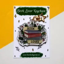 sleutelhanger van een stapel boeken met een lint er omheen met de tekst book lover. om de boeken zijn verschillende winterse planten te zien